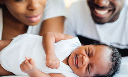 Black family smiling at a baby