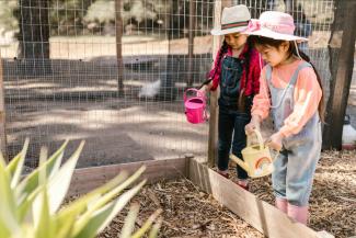 Two children in a garden with watering cans
