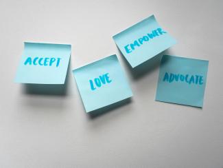 Blue post-it notes that read "accept," "love," "empower," "advocate"