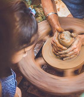 little girl watching adult make pottery