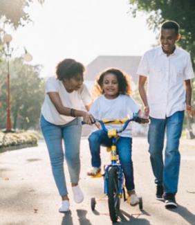 parents teaching child how to ride a bike
