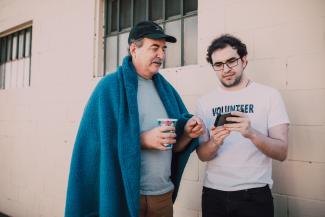 Two men talking and looking at a phone