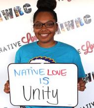 Tanae LeClare holding up sign that says Native love is unity