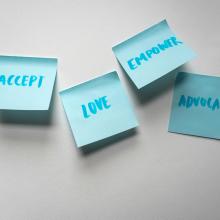 Blue post-it notes that read "accept," "love," "empower," "advocate"