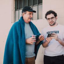 Two men talking and looking at a phone